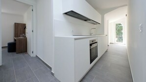 Et moderne køkken med hvide skabe, en indbygget ovn og et rustfrit stål emfang.