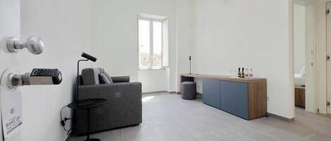 A modern, minimalist living room with a grey sofa, a small side table, and a wooden cabinet.