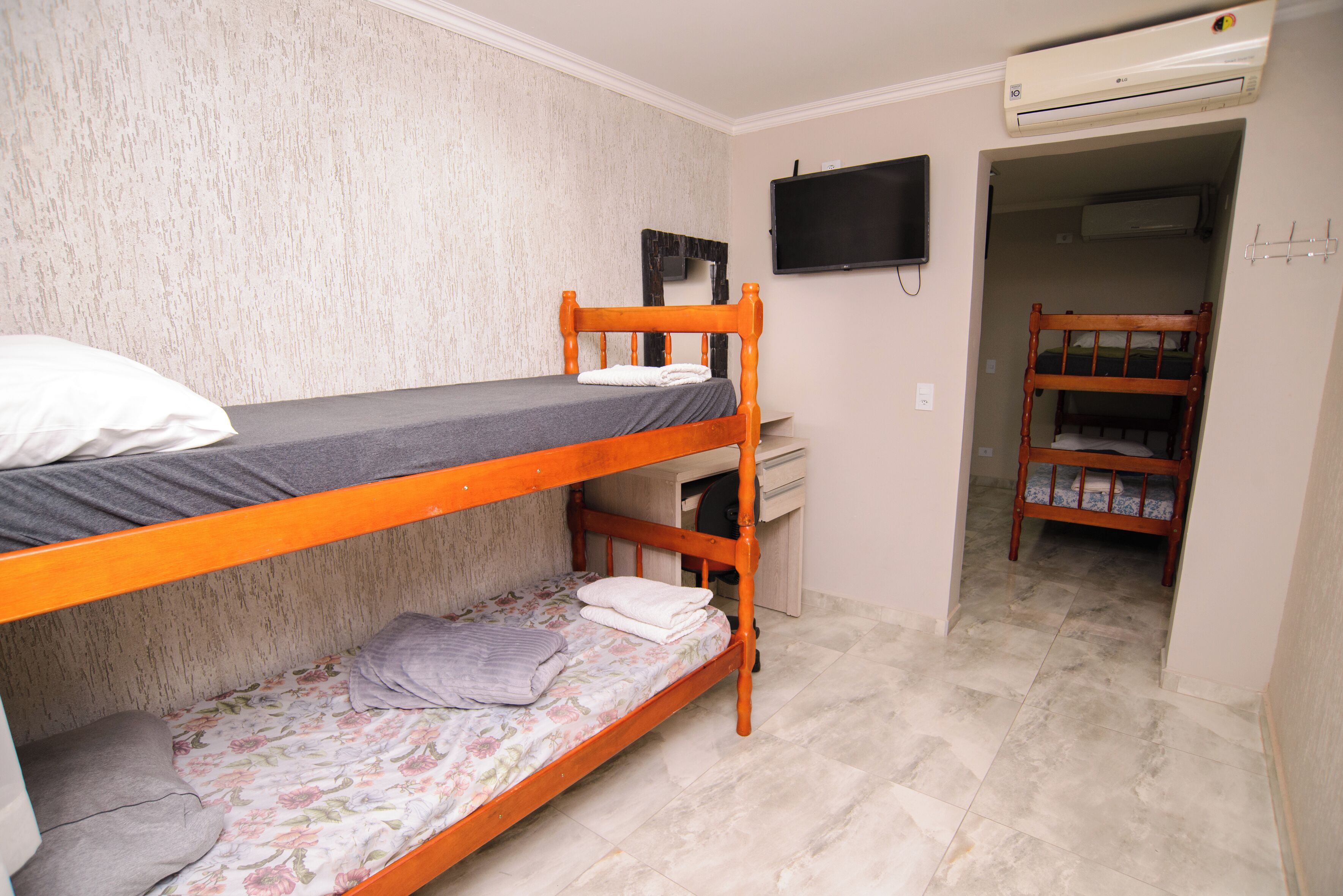 Una camera con un letto a castello, una televisione a schermo piatto e un condizionatore d'aria a parete.