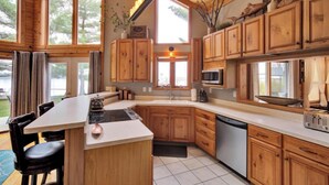 A modern kitchen with wooden cabinets, a central island, and large windows. - Lake front cottage less than 20 min from golf simulator/pool/bar/grill (Arkdale)