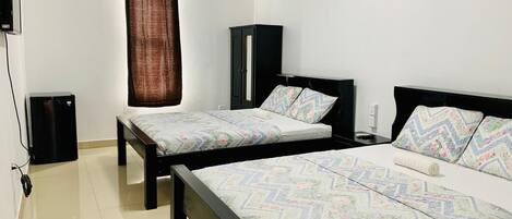 A bedroom with two beds, a wardrobe, and a TV.
