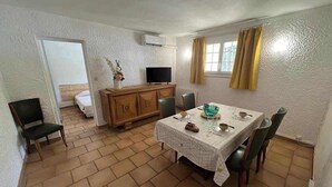 Een eetgedeelte met een tafel voor vier personen, een televisie en een kast.
