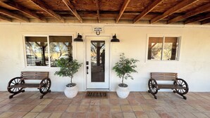 A ranch-style building with a wooden porch, two potted plants, and two wooden benches. - Private ranch getaway perfect for stargazing, relaxing pool desert hot bsprings  (Desert Hot Springs)
