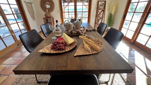 A dining table with a woven placemat, a bottle, wine glasses, cheese, grapes, and bread. - Private ranch getaway perfect for stargazing, relaxing pool desert hot bsprings  (Desert Hot Springs)