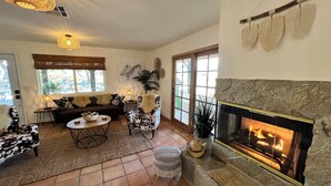 A cozy living room with a fireplace, a sofa, a coffee table, and a patterned armchair. - Private ranch getaway perfect for stargazing, relaxing pool desert hot bsprings  (Desert Hot Springs)