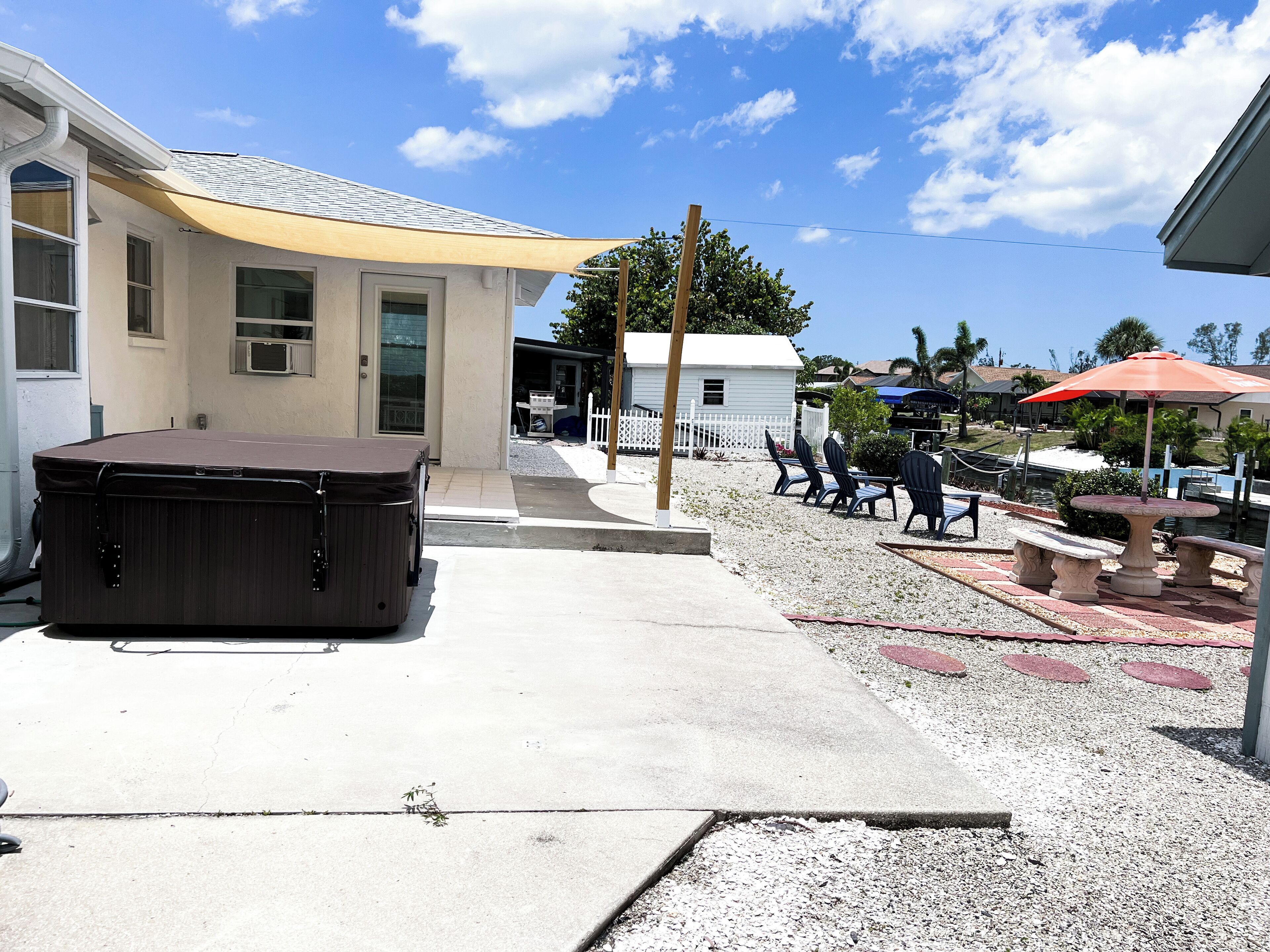 A patio area with outdoor seating, a hot tub, and a small building with a white exterior.