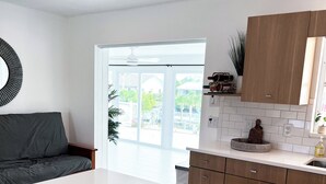A modern kitchen with white countertops, wooden cabinets, and a large window offering a view of the outdoors.