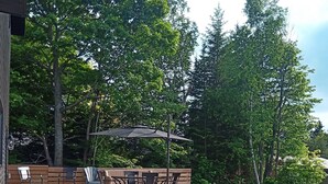 A wooden deck with outdoor furniture, a barbecue grill, and a stone wall. - House in Sauble Beach hosted by Maleeha and Raza. (Sauble Beach)