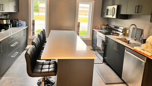 A modern kitchen with a central island, dark cabinets, stainless steel appliances, and large windows. - House in Sauble Beach hosted by Maleeha and Raza. (Sauble Beach)