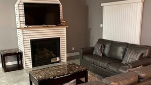 A living room with a fireplace, a leather sofa, and a coffee table. - House in Sauble Beach hosted by Maleeha and Raza. (Sauble Beach)