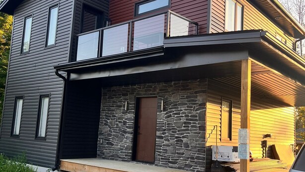 A modern two-story house with a stone facade, a balcony, and a covered porch area. - House in Sauble Beach hosted by Maleeha and Raza. (Sauble Beach)