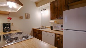 A compact kitchen with a stove, microwave, sink, and dishwasher. - Condo close to the Chile Express (Angel Fire)