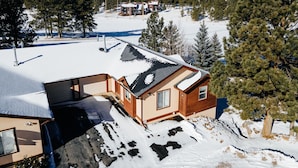 A cabin with a sloped roof, surrounded by snow-covered ground and dense forest. - Townhome with 1st Hole Golf Course Views (Angel Fire)