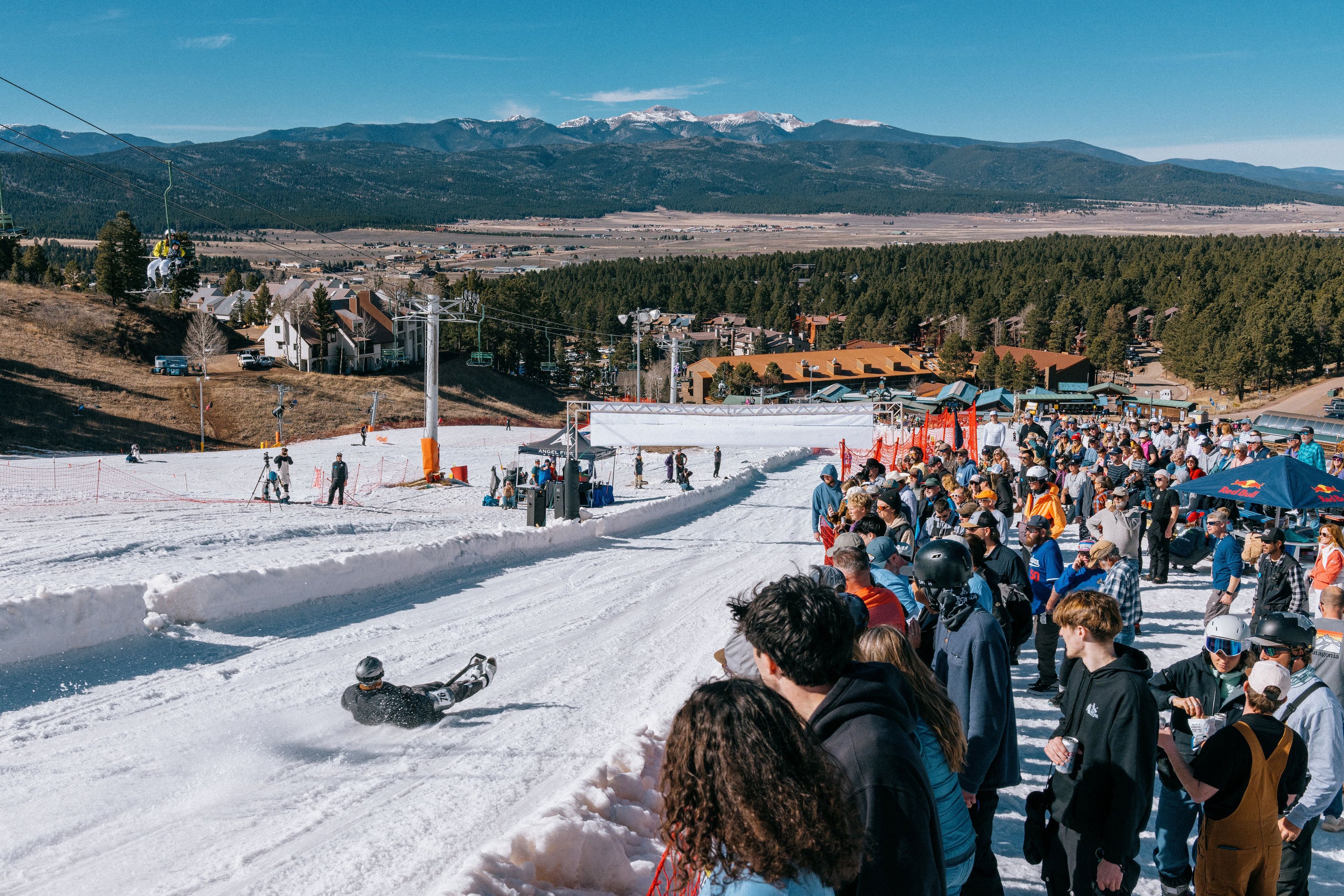 Une piste de ski avec beaucoup de monde, un télésiège et une montagne en arrière-plan.