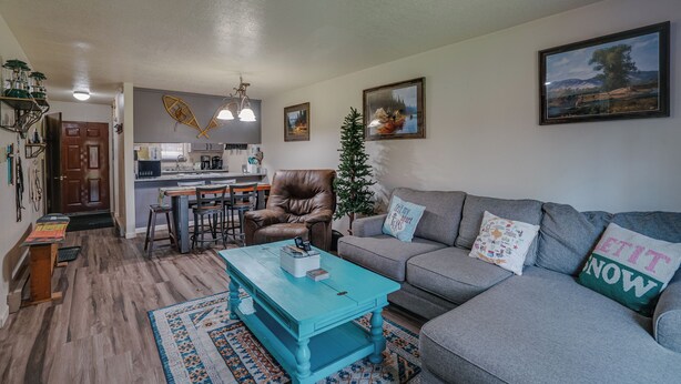 A living room with a grey sofa, a blue coffee table, and a small Christmas tree. - Comfy Condo near Shuttle Pick up (Angel Fire)