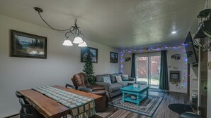 A living room with a wooden dining table, leather chairs, a grey sofa, and a turquoise coffee table. - Comfy Condo near Shuttle Pick up (Angel Fire)