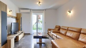 Un salon moderne avec un canapé en cuir, un téléviseur à écran plat et un meuble de rangement en bois.