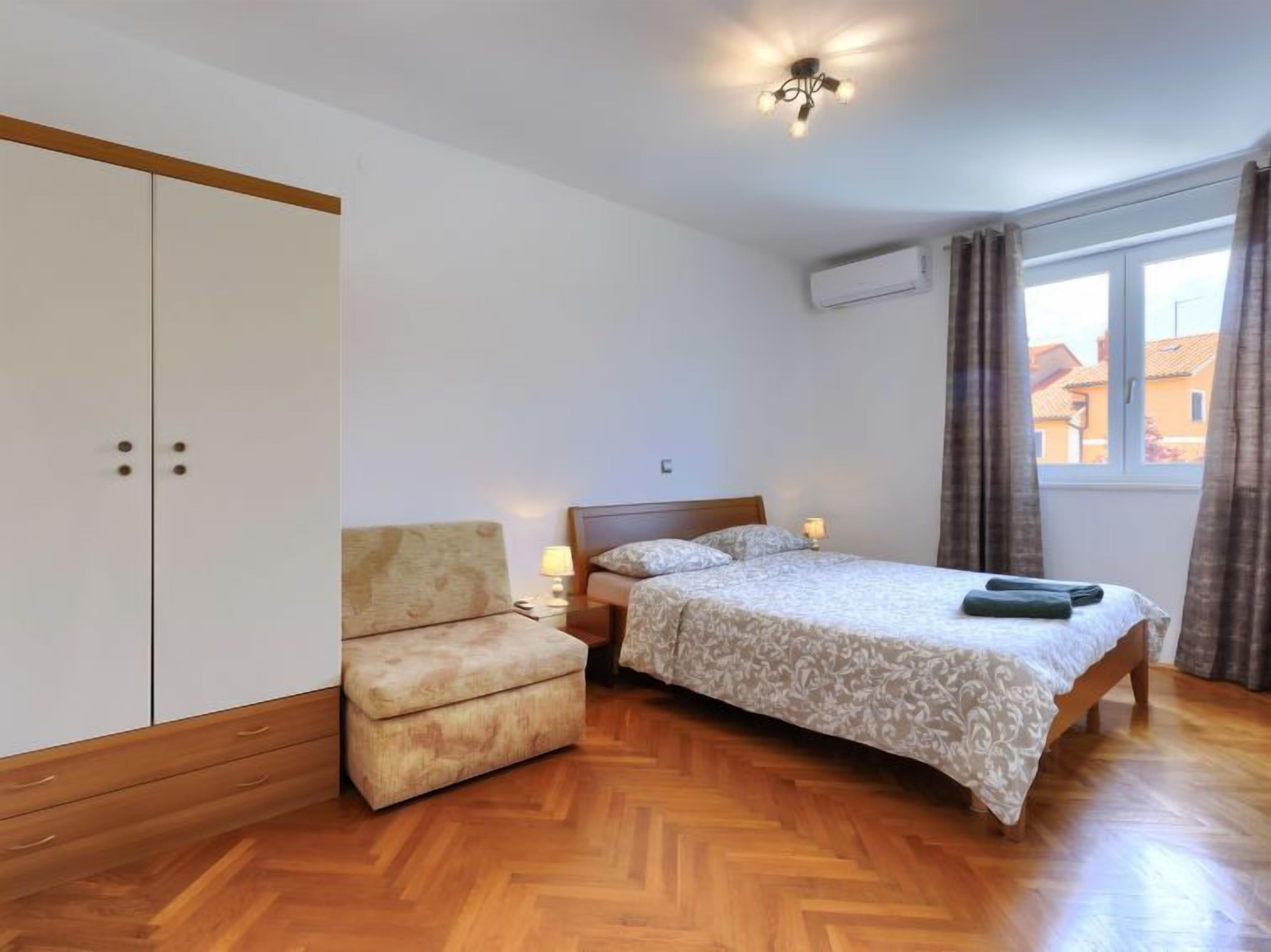 A bedroom with a bed, a nightstand, a chair, and a wardrobe.