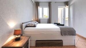 Une chambre à coucher avec un lit, une table de chevet, une lampe et une fenêtre avec des rideaux.