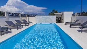 Un espace piscine avec des chaises longues et un ciel dégagé.