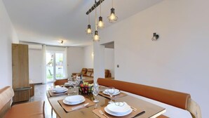 Un espace repas moderne avec une table en bois pour quatre personnes, des bancs en cuir et des luminaires suspendus.