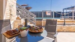 A terrace with a table set for a meal, overlooking a pool area with a railing and a sign. - Thrapsano House for up to 8 Persons, Near Iraklion (Minoa Pediada)