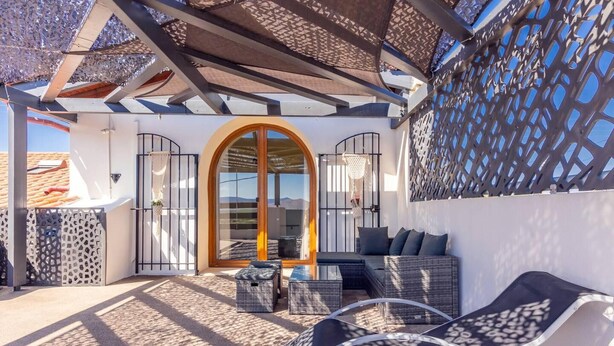 A sunlit outdoor seating area with a large arched doorway, wicker furniture, and a lattice wall. - Thrapsano House for up to 8 Persons, Near Iraklion (Minoa Pediada)