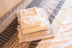 A neatly folded white towel stacked on a striped fabric, placed on a textured bedspread. - Vanellus Villas Sleeps 6 With Jacuzzi (Pakostane)