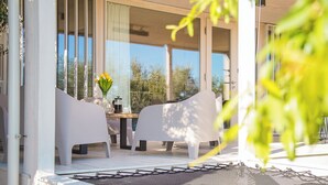 A modern outdoor seating area with white chairs and a table, a coffee maker, and a vase with flowers. - Vanellus Villas Sleeps 6 With Jacuzzi (Pakostane)