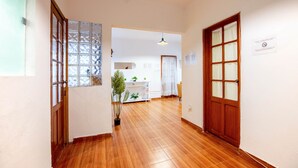 A hallway with wooden flooring, a potted plant, a ceiling light, and a door with a window. - Loft in Roma Sur: King Size Bed (Cuauhtémoc)