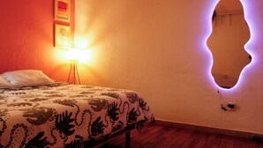 A bedroom with a bed, a wall-mounted mirror, and a floor lamp. - Loft in Roma Sur: King Size Bed (Cuauhtémoc)