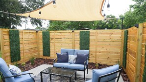 A patio area with a wooden fence, a blue sofa set, and a table. - Cozy 1 bedroom suite-apartment. (Port Richey)