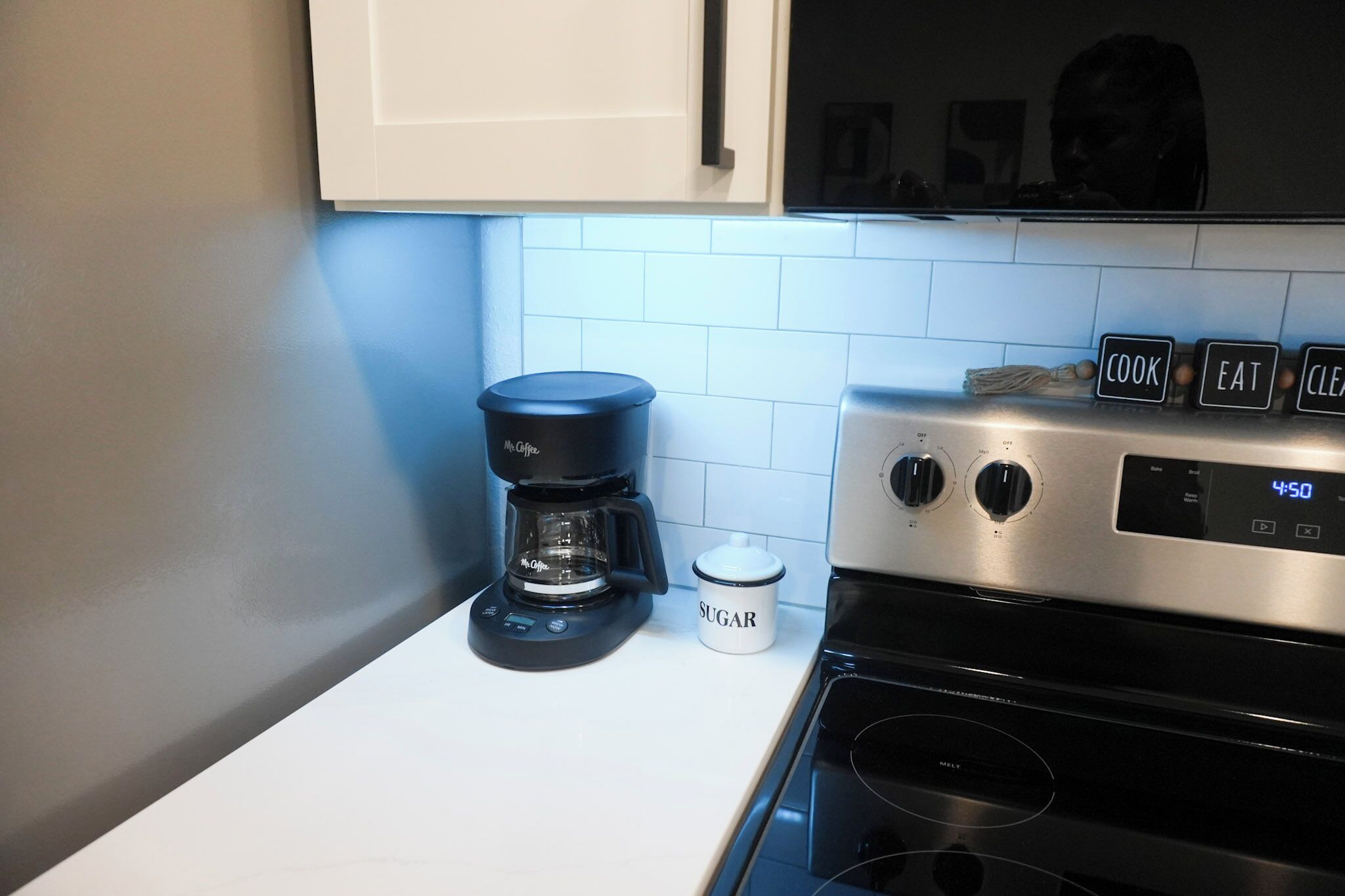 A kitchen with a coffee maker, a sugar container, and a microwave.