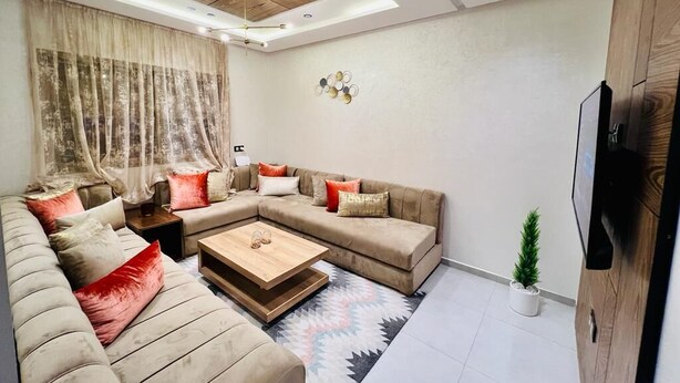 A modern living room with a sectional sofa, a coffee table, and a TV mounted on the wall.