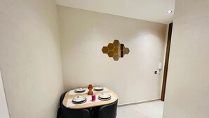 A dining area with a table set for four, black chairs, and a decorative wall piece.