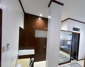 A compact room with a kitchenette, a bed, and a bathroom. - 18 La Guardia Ext (Cebu City)