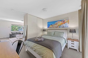 A modern bedroom with a bed, bedside tables, a desk, and a sofa.