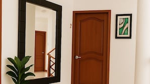 Un pasillo con una puerta de madera, un espejo grande y un cuadro en la pared.