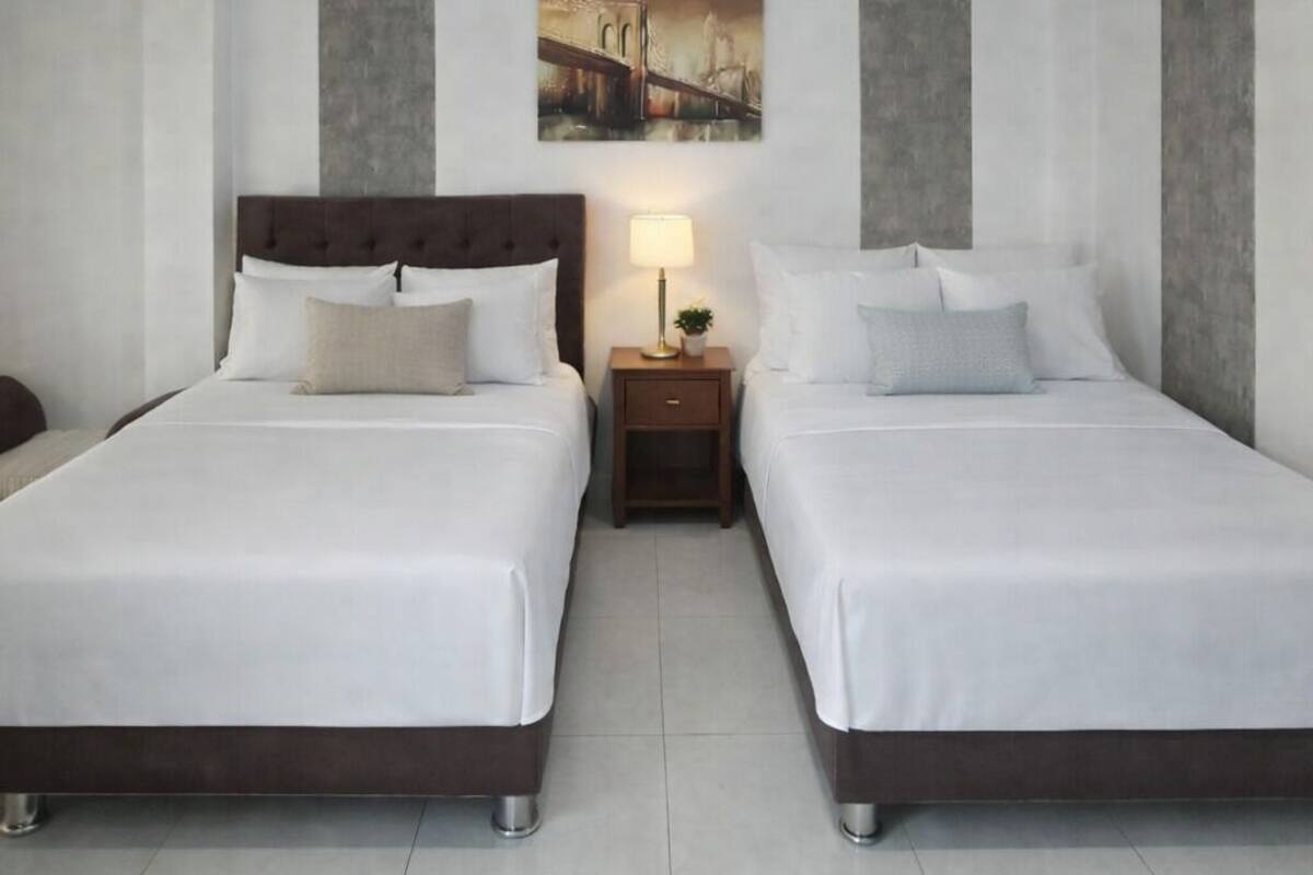 Ein Hotelzimmer mit zwei Betten, einem Nachttisch mit Lampe und einem Bild an der Wand.
