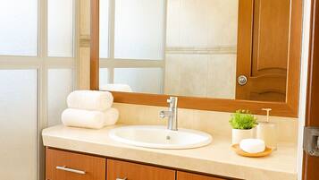 A modern bathroom with a large mirror, a sink, and wooden cabinets.