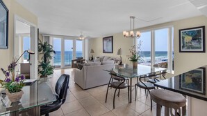 Amplia sala de estar con un sofá grande, una mesa de comedor de vidrio y vistas al océano.