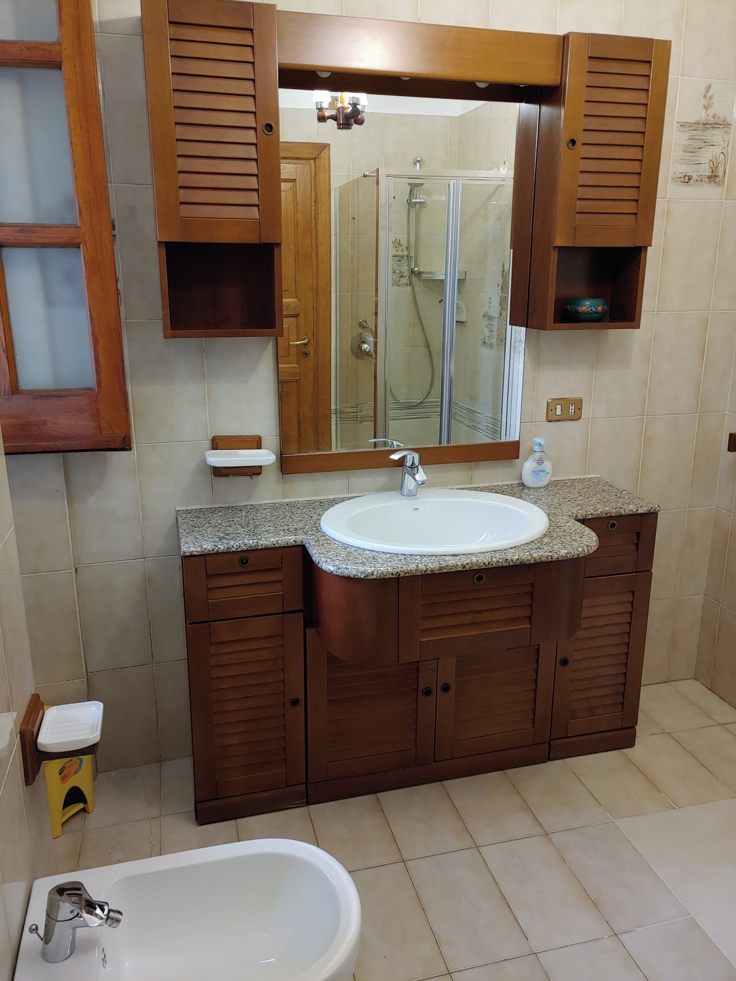 Ein Badezimmer mit einem Holzbadschränken, einem Waschbecken, einem Spiegel, einer Dusche und einer Badewanne.