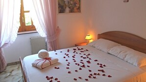 A neatly made bed with rose petals, a rolled towel, and a painting on the wall. - Villa La Favola Suite Ischia Terrace with view (Barano D'ischia)