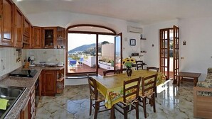 A spacious kitchen with a dining area, large windows, and a view of the outdoors. - Villa La Favola Suite Ischia Terrace with view (Barano D'ischia)