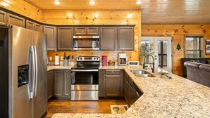 A modern kitchen with stainless steel appliances, granite countertops, and wooden cabinetry.