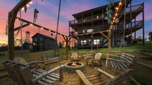 A wooden deck with outdoor seating and a fire pit, overlooking a two-story building with a balcony.