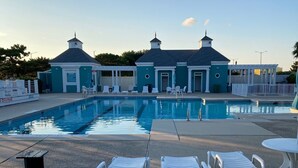 A swimming pool with lounge chairs and a small building with a pointed roof. - BEAUTIFULLY DECORATED ~ CLOSE TO THE BEACH ~ 5 BEDROOM/4 BATH  (Corolla)