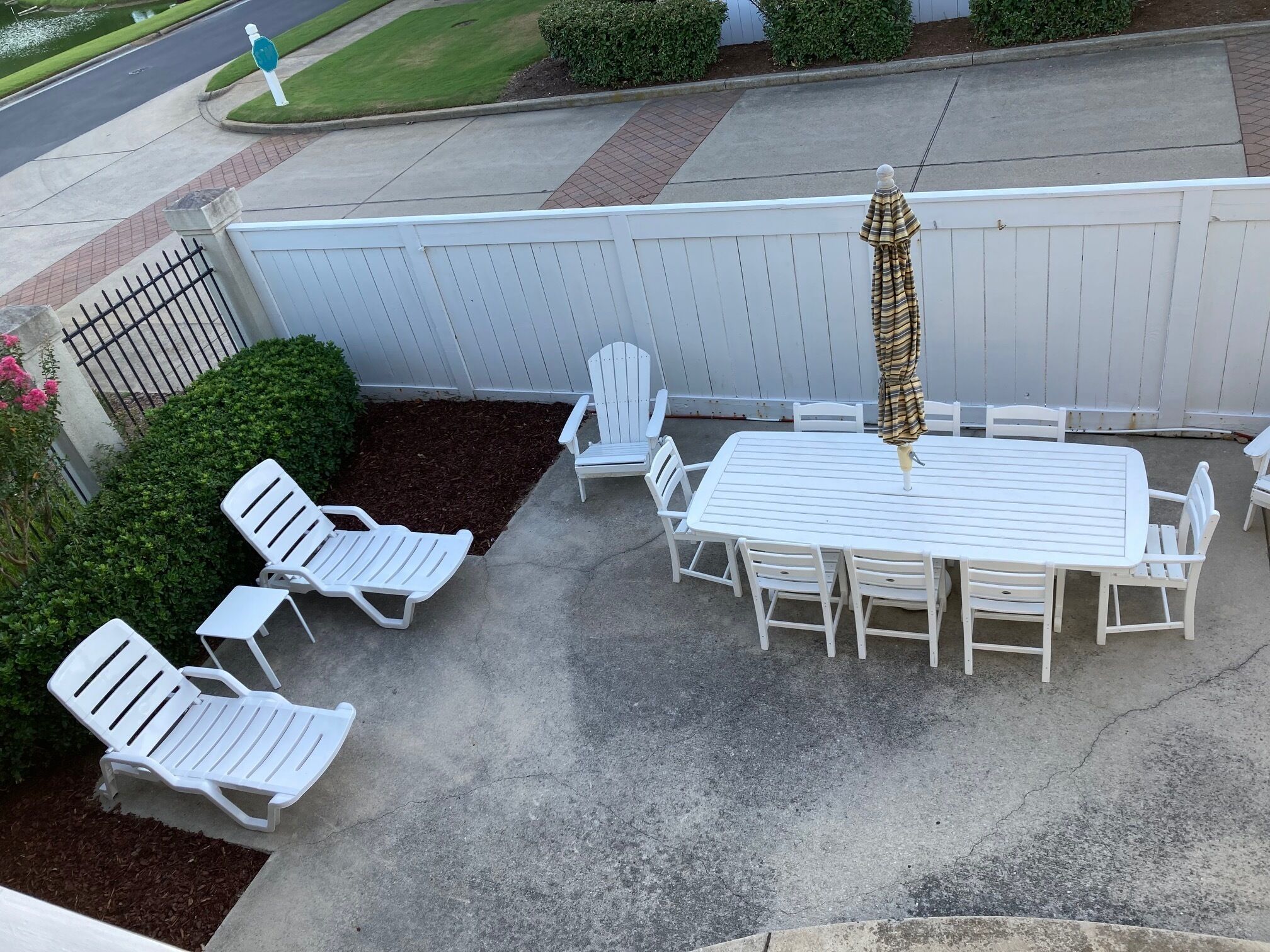Eine Terrasse mit weißem Tisch und Stühlen, umgeben von einem weißen Zaun.