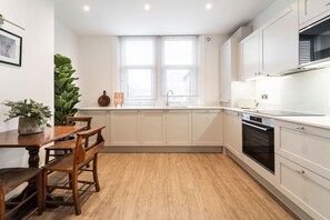 A modern kitchen with white cabinets, a wooden dining table, and chairs.