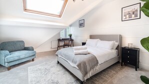 Een slaapkamer met een bed, een bureau, een stoel, een nachtkastje en een raam.